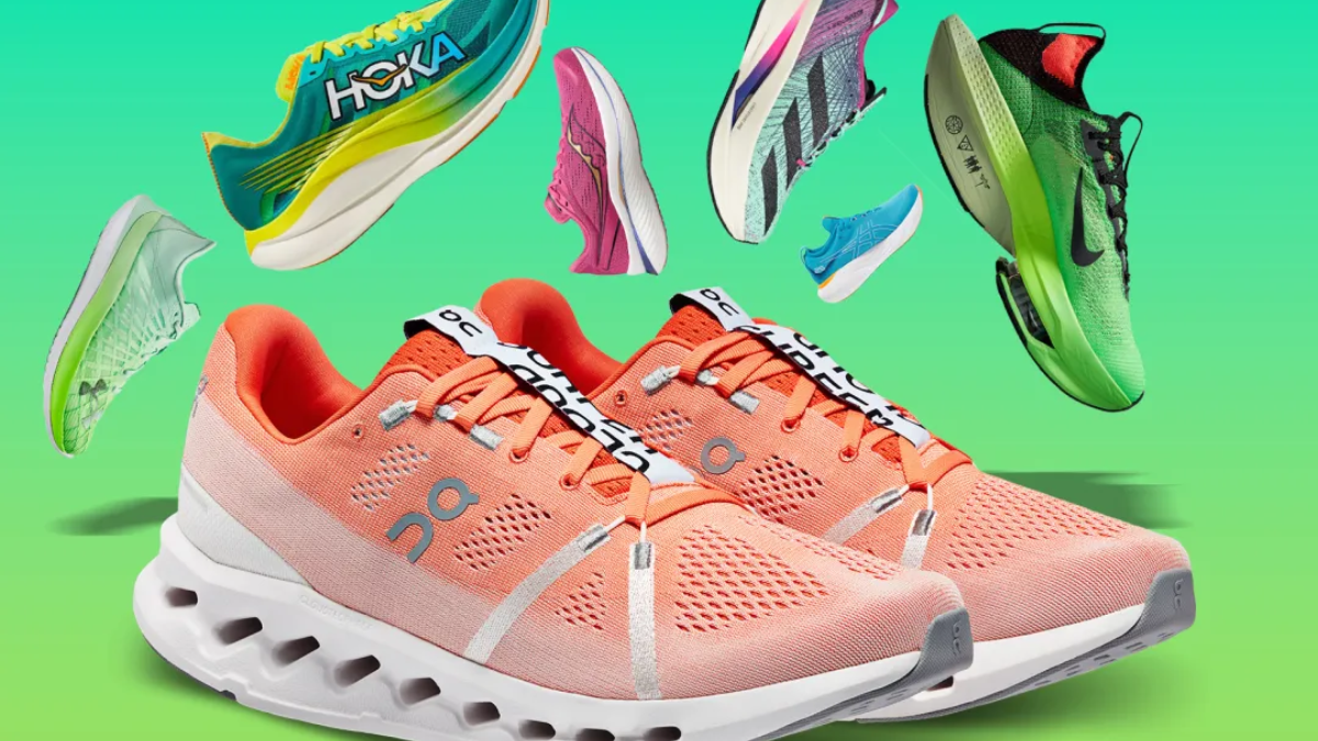 Một đôi giày chạy bộ màu cam tươi sáng với đế trắng và gót đen, nổi bật giữa các đôi giày chạy bộ khác nhau về màu sắc và kiểu dáng.