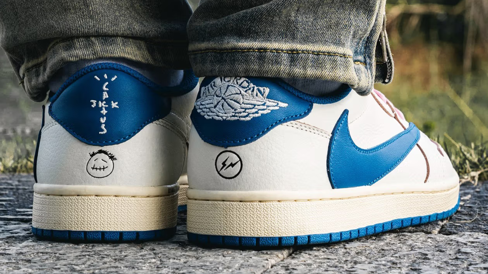 Hinh anh 1: Travis Scott x Fragment x Air Jordan 1 Low OG voi logo Swoosh nguoc va mau xanh Military Blue tren nen da trang.