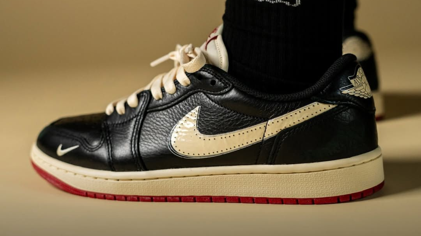 Hinh anh 1: Air Jordan 1 Low OG “Nitro” voi phoi mau Black/Muslin/Varsity Red, thiet ke boi Nigel Sylvester, bieu tuong thoi trang biker mua thu 2025.